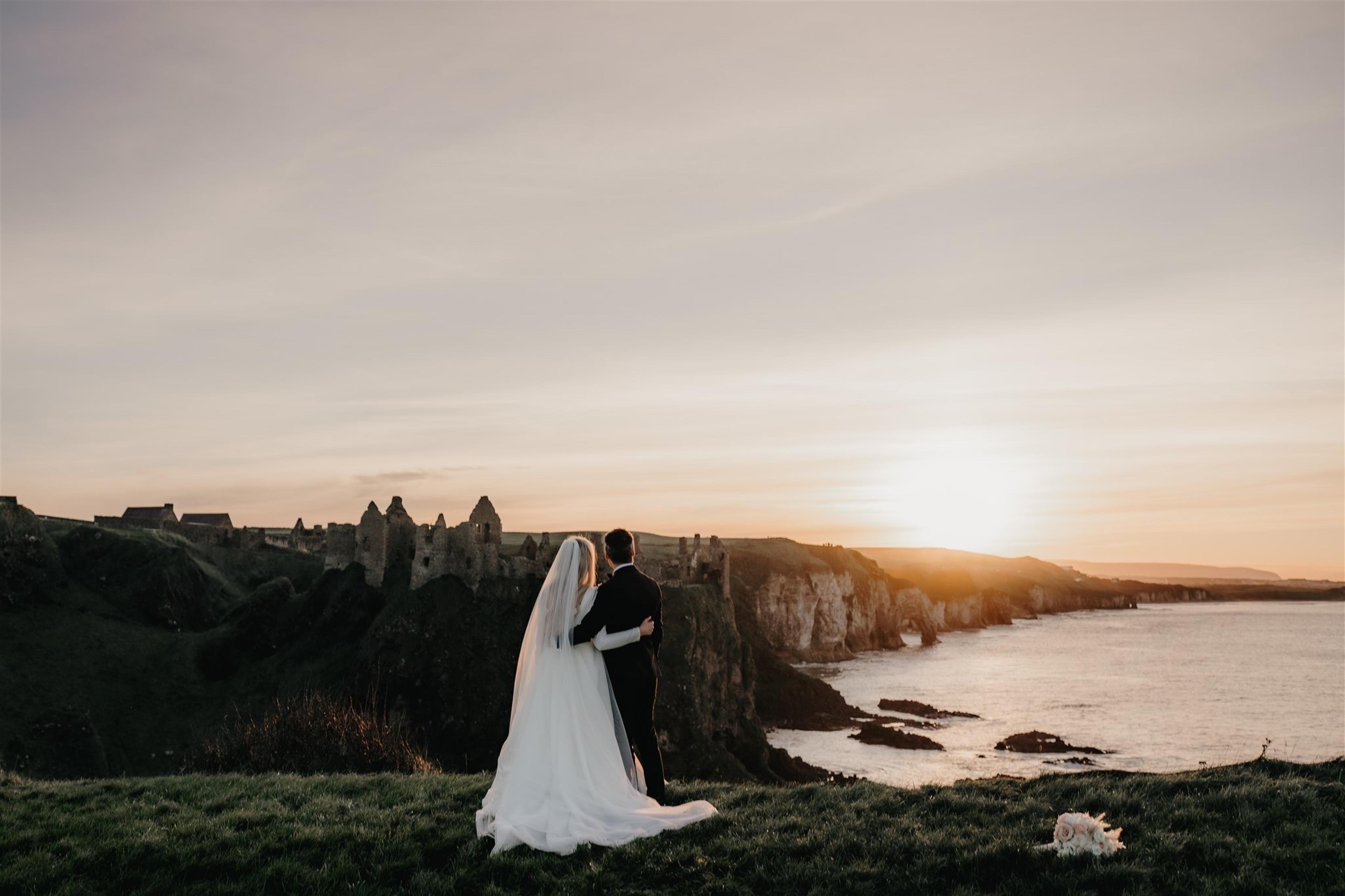 Couple standing on cliff at sunset, overlooking castle